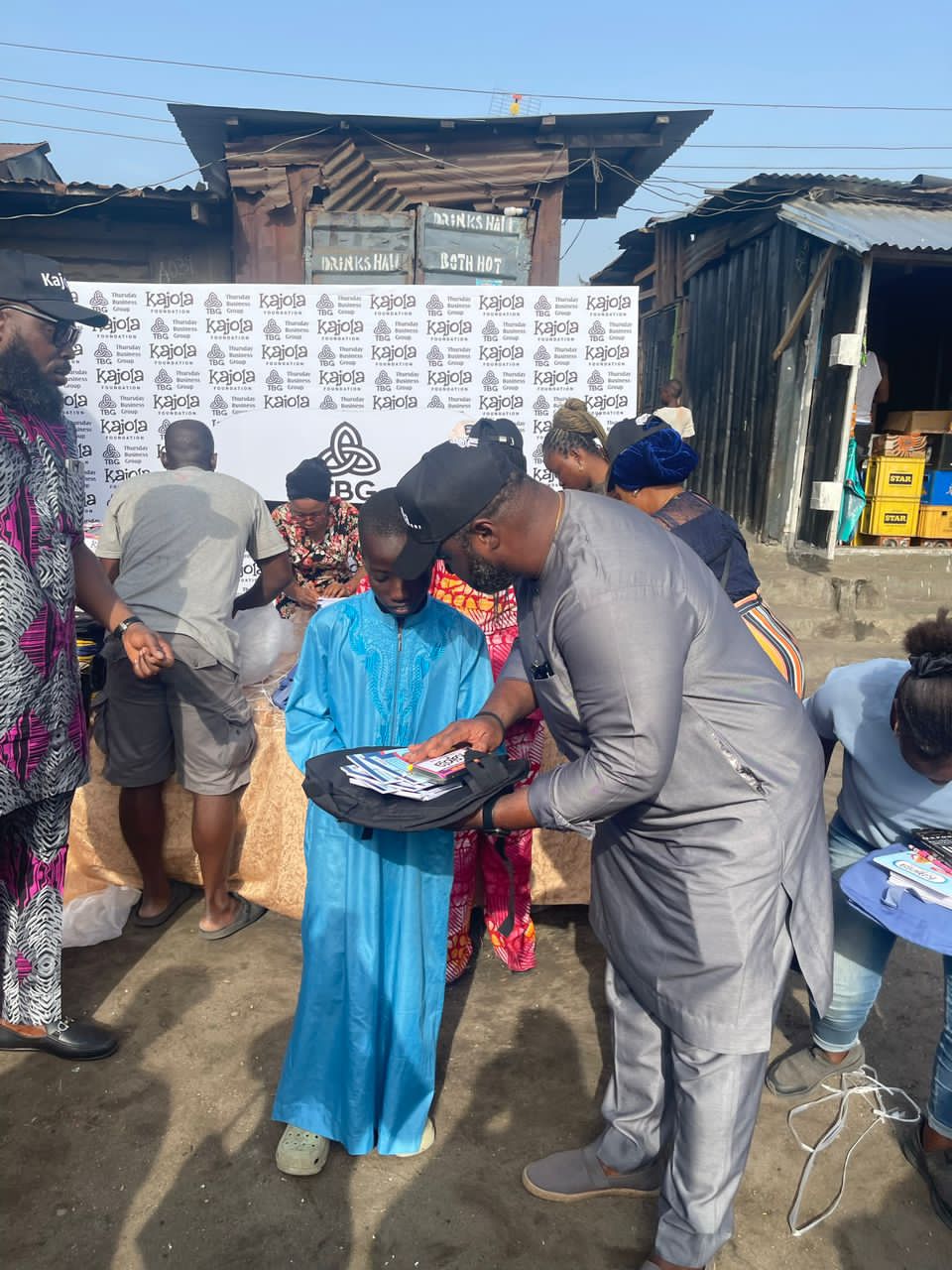 Volunteer handing a school bag to a boy at a Kajola Foundation outreach