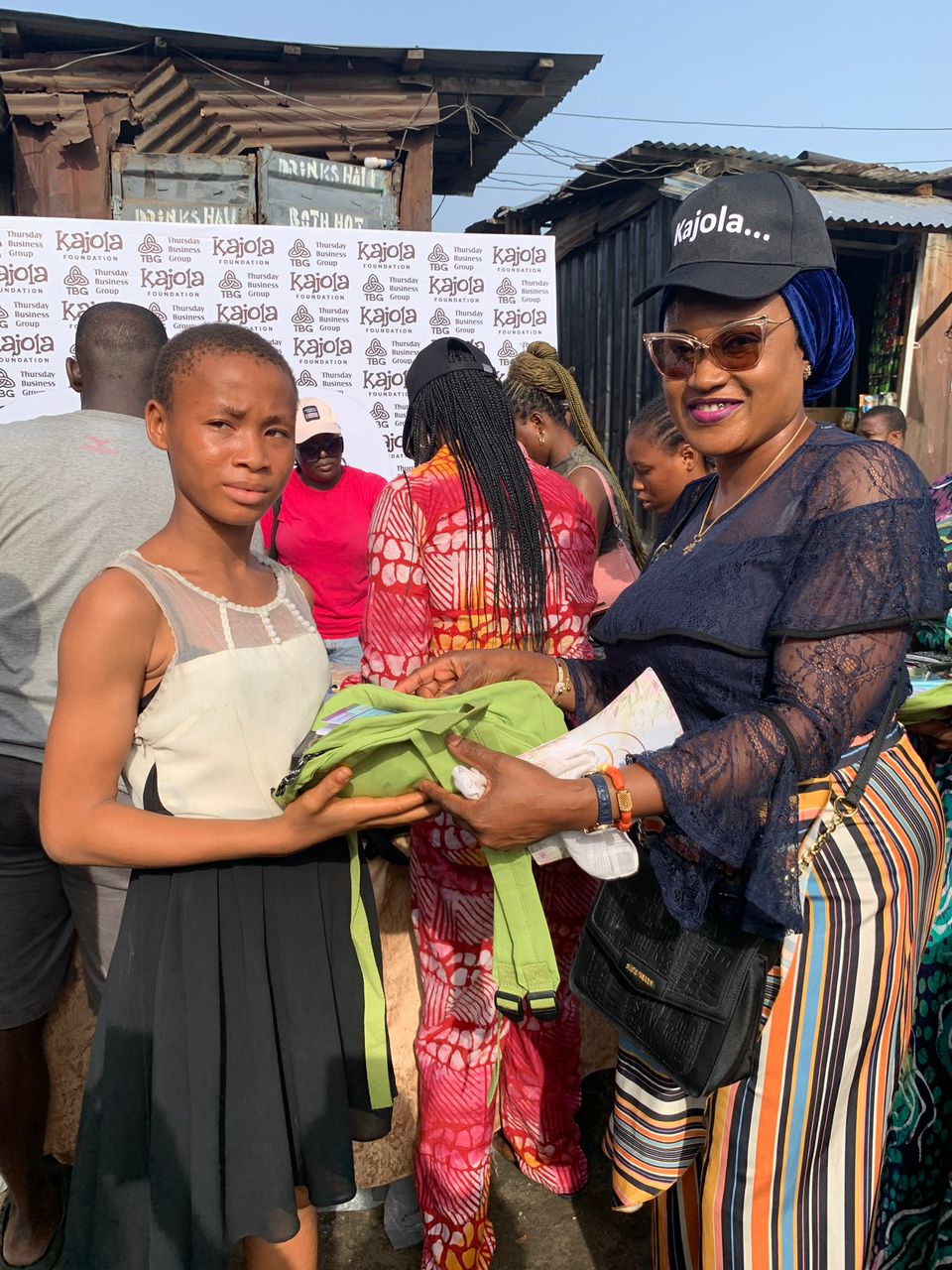 Kajola Foundation member handing school materials to a girl